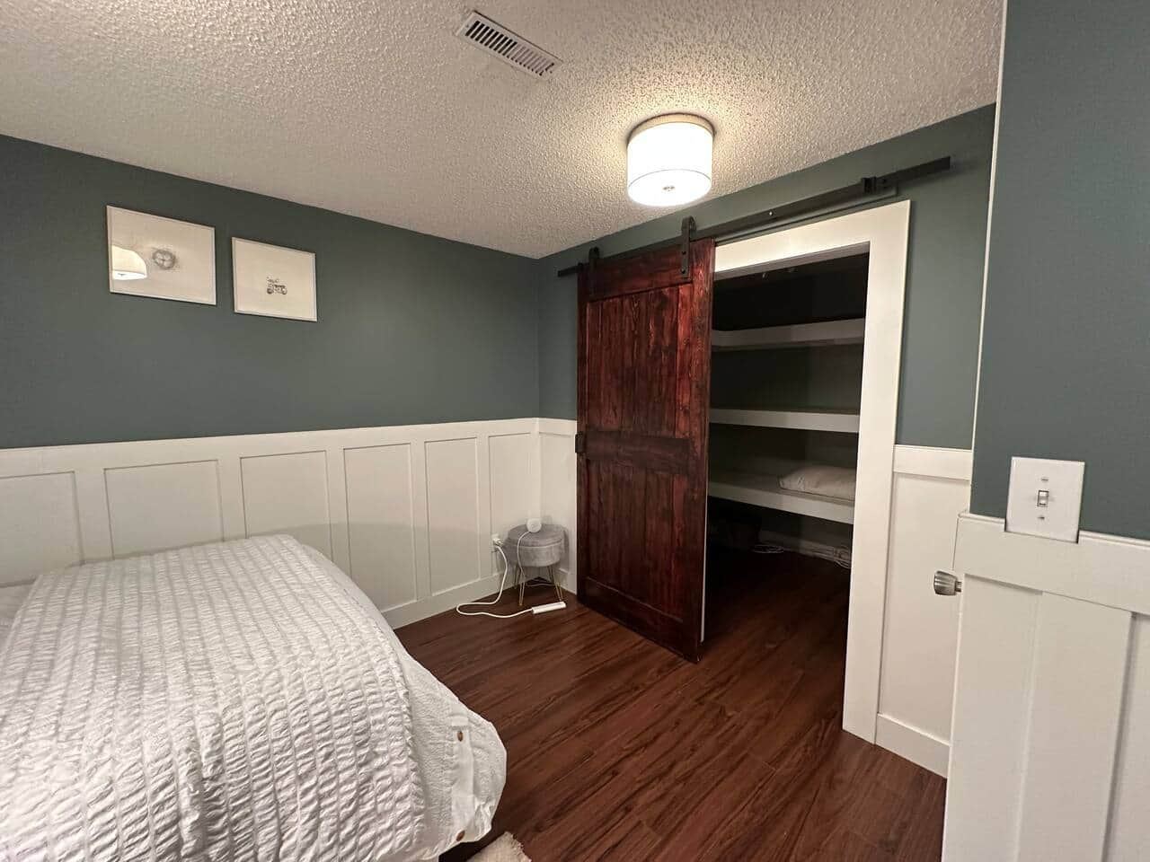Bedroom with white bedding and an open barn door to the closet